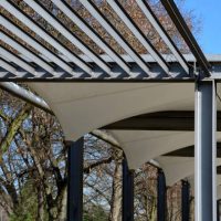 white canvas stretched, shading from the sun and rain over the terrace of the restaurant, on the playground in the kindergarten, on the platform of the promenade. pergola with metallic gray beams for climbing plants, tense, taut, stretch, blinds shadow, tarp