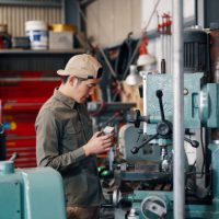 Mid adult male checking the metal he is milling in factory in Japan