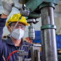 Asian Engineer work with drill machine in industrial manufacturing  factory , hard work concept