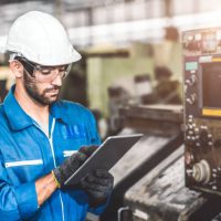 engineer setup the CNC machine with G-Code programming upload from Computer Tablet for technology in heavy industry.