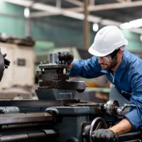 Industrial engineer worker in white hard hat working with production machinery in the factory